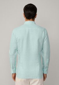 Lichtblauw knoopshirt met een verticale gestreepte patroon, lange mouwen en manchetten met knopen, voorzien van een traditionele kraagontwerp.