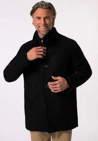 Abrigo de lana negro con un cuello alto, con cierre de cremallera y dos botones en la parte delantera. La tela tiene una textura suave con un ligero brillo.