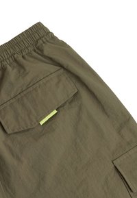 Olijfgroene cargobroek met een elastische tailleband, zakdetails en een subtiele textuur. Bevat een contrasterend geel label op de zak.