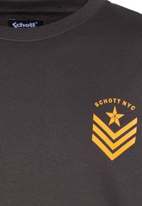 T-shirt grigio scuro in cotone con collo rotondo, caratterizzata da una grafica arancione di una stella e chevron sul petto sinistro.