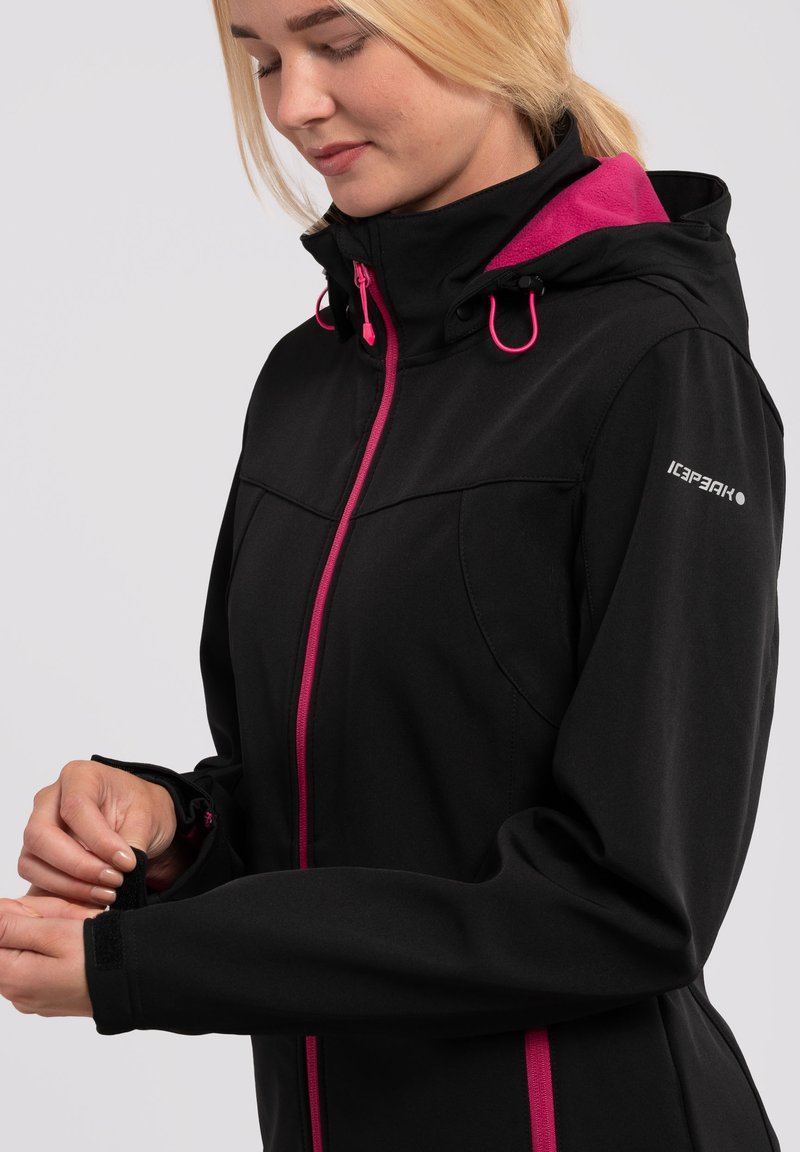 Giacca softshell nera con dettagli rosa, colletto alto, cappuccio regolabile e chiusura con zip. Presenta chiusure sui polsi e un logo sulla manica.