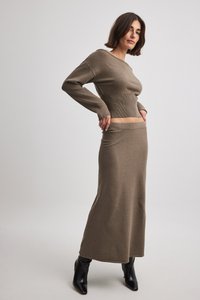 Ensemble en tricot deux pièces de couleur vert olive ; crop top ajusté à manches longues avec un large décolleté et une jupe longue assortie avec une ceinture.