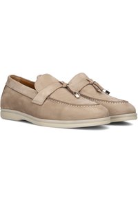 Beige suede instappers met een ronde neus, decoratieve strikdetails en een witte rubberen zool. Kenmerkt zich door contrasterende stiksels langs de bovenkant.