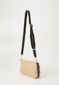 Splotkowana beżowa torba crossbody o błyszczącej fakturze, czarnym, regulowanym pasku, złotych elementach i prostokątnym kształcie.
