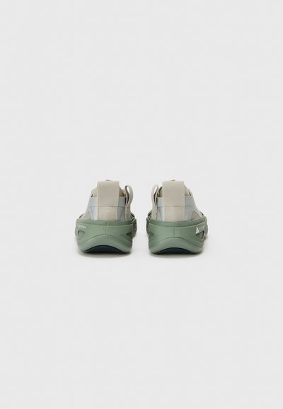 Back view of lightweight shoes in pale gray and green, featuring a textured sole and elastic straps for secure fit.