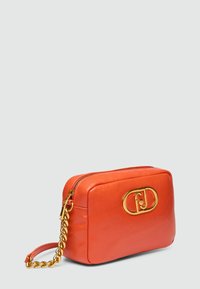 Geantă din piele portocalie tip crossbody, cu o formă rectangulară, curea din lanț auriu și un logo auriu proeminent pe partea din față. Închidere cu fermoar în partea de sus.