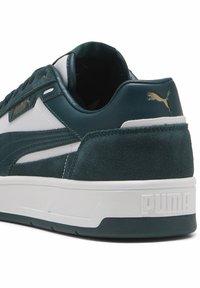 Grønne ruskinds- og lædersneakers med hvide accenter og en tykk hvid sål. Har et guldlogo og tekstureret hæl.