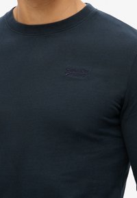 Navyblaues Baumwolllongsleeve T-Shirt mit Rundhalsausschnitt, versehen mit einem kleinen, gestickten SuperDry-Logo auf der Brust.