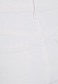 Vita denimjeans med en slät yta, med två bakfickor och diskret sömnad längs sömmarna. Tydligt hög midja.