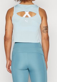 Jasnoniebieski sportowy crop top z siatkowatą teksturą i plecami w kształcie krzyża. Połączony z odpowiednimi, dopasowanymi legginsami o wysokim stanie w tym samym kolorze.