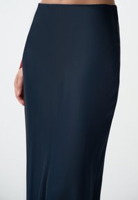 Gonna lunga blu navy realizzata in tessuto morbido ed elasticizzato, con una silhouette aderente e un delicato dettaglio nella cucitura laterale.