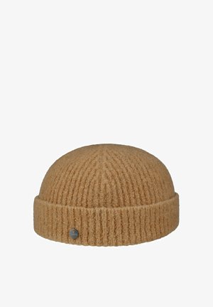 Camel-colored ribbed knit beanie with folded cuff and small circular metal brand tag on cuff.