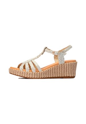 Sandalia cuña con suela plataforma beige tejida y tiras blancas trenzadas, con hebilla en el tobillo y diseño de punta abierta.
