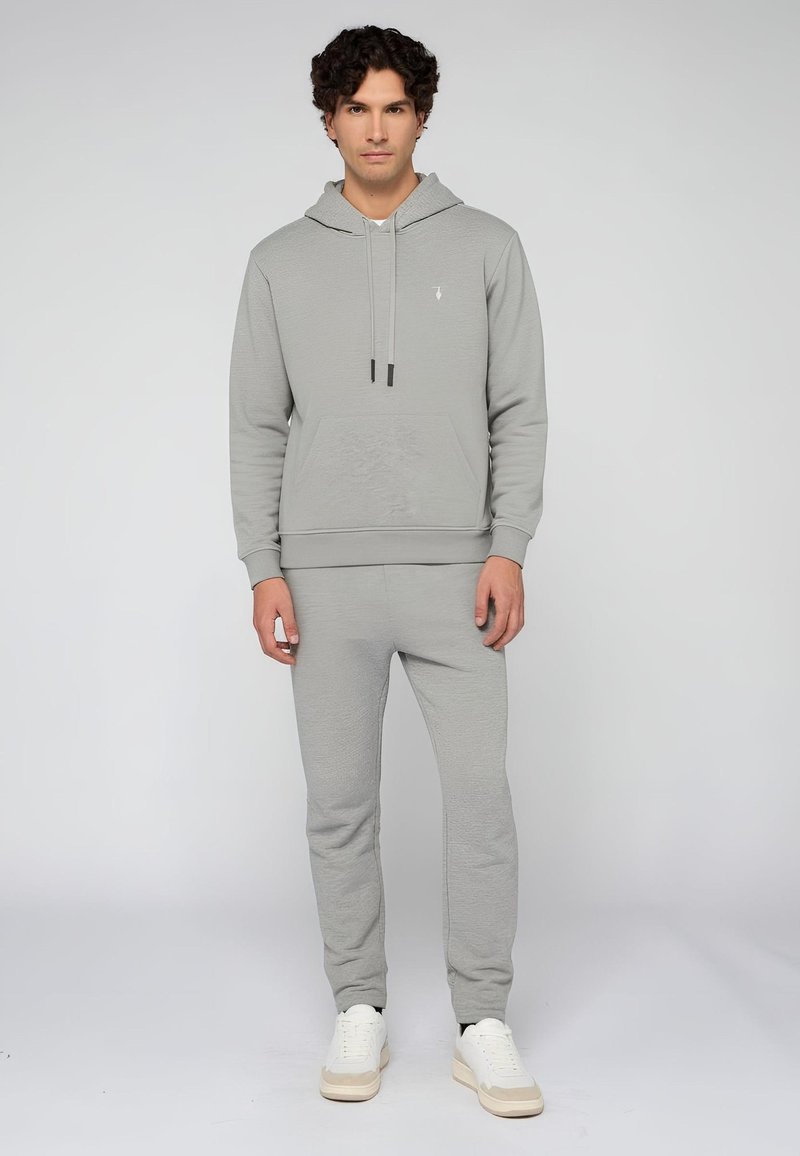 Světle šedá mikina a souprava tepláků s přední kapsou, šňůrkami a manžetami. Vyrobeno z měkké, texturované tkaniny.