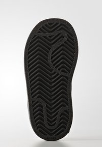 Svart gummisula till sneaker med ett zigzag-mönster och släta, rundade kanter. I mitten finns en distinkt böjd design.