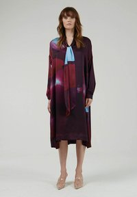 Langarm jurk in diep paars met blauwe en rode abstracte patronen, voorzien van een nekstrik. Glad stof met zijsplits voor extra stijl.
