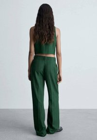 Top court rayé vert et pantalon large taille haute assorti. Le tissu semble lisse. La tenue est ajustée à la taille, avec des lignes verticales.