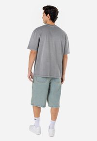 Grå bomulls t-skjorte med korte ermer, rund hals og avslappet passform, sammen med lyseblå denimshorts og hvite joggesko.