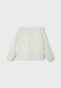 Blusa blanca de manga larga con una tela texturizada, detalles de hombros fruncidos y una apertura en la parte posterior con forma de llave y cierre de botón pequeño.