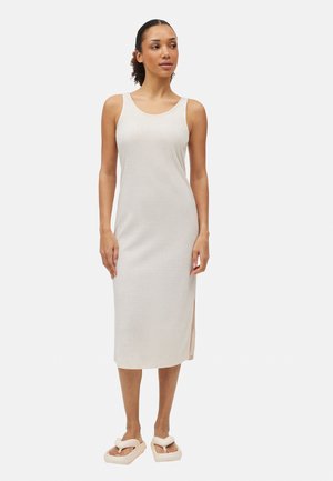 Vestido midi acanalado en color beige claro, con corte recto, tirantes anchos y aberturas laterales. Modelo combinado con sandalias suaves de color claro.
