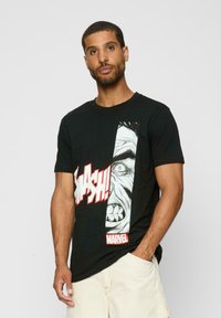 Black cotton t-shirt featuring a large graphic of an angry face and the word "SMASH!" in red text, with a white "MARVEL" logo at the bottom.