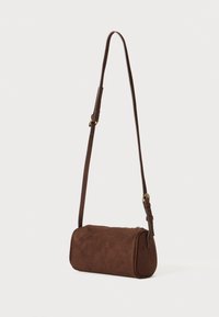 Borsa a tracolla in suede marrone con forma cilindrica, tracolla regolabile e chiusura con zip, caratterizzata da una texture liscia e hardware minimal.