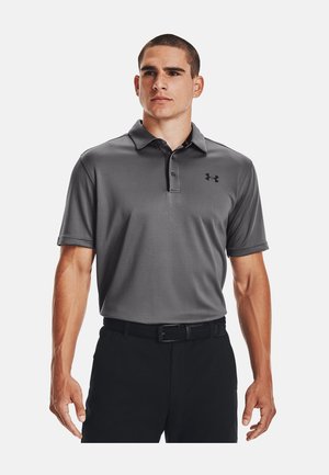 Polo grigio con tessuto a trama, maniche corte e colletto. Presenta un logo Under Armour nero sul lato sinistro del petto, abbinato a pantaloni neri.
