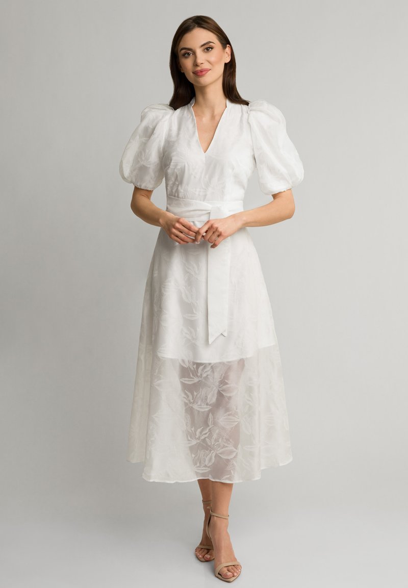 Biała midi sukienka z bufiastymi rękawami, dekoltem w kształcie V i dopasowaną talią. Posiada warstwową, przezroczystą tkaninę z kwiatowymi wzorami oraz szczegół z wiązanym paskiem.