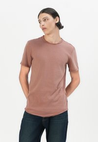 Kurzärmeliges T-Shirt mit Rundhalsausschnitt in gedämpftem Rosa. Aus weichem Material mit sichtbaren Nähdetails und einem leicht geschwungenen Saum.