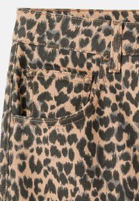 Džínovina s leopardím vzorom má béžový základ a čierne a tmavohnedé škvrny. Obsahuje zadnú kapsu a kontrastné steh.