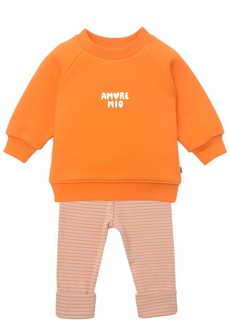 Oranger Baumwoll-Sweatshirt mit weißem "AMORE MIO"-Text, kombiniert mit beige-orange gestreiften Leggings mit aufgerollten Säumen.