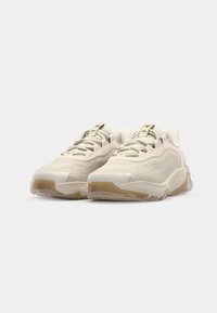 Scarpe sportive di colore beige chiaro con una tomaia texturizzata, chiusura con lacci e dettagli logati sottili. Sole in gomma spesso con accenti traslucidi.