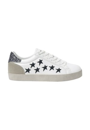 Zapatilla blanca con apliques de estrella negra, talón de ante gris y acento de purpurina. Punta redondeada y suela de goma plana, con cordones en la parte delantera.