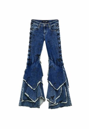 Blue denim flared jeans with layered ruffle design, featuring black lace-up details along the sides and frayed edges.
