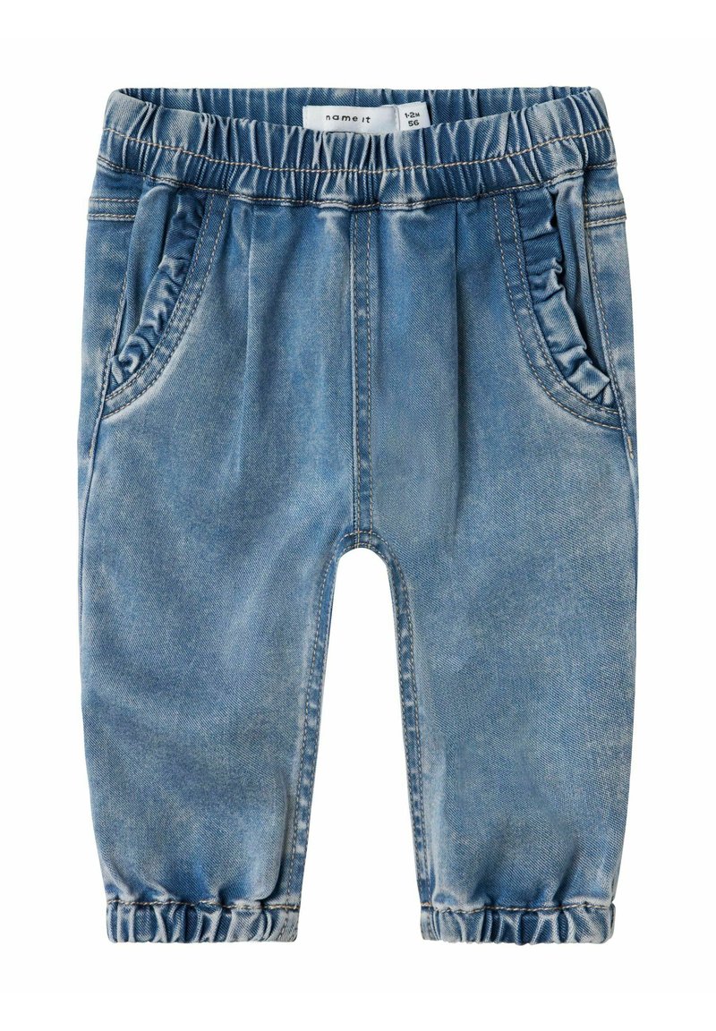 Los pantalones de mezclilla azul cuentan con una cinturilla elástica, bolsillos laterales y puños fruncidos en los tobillos. La tela tiene una textura desgastada.