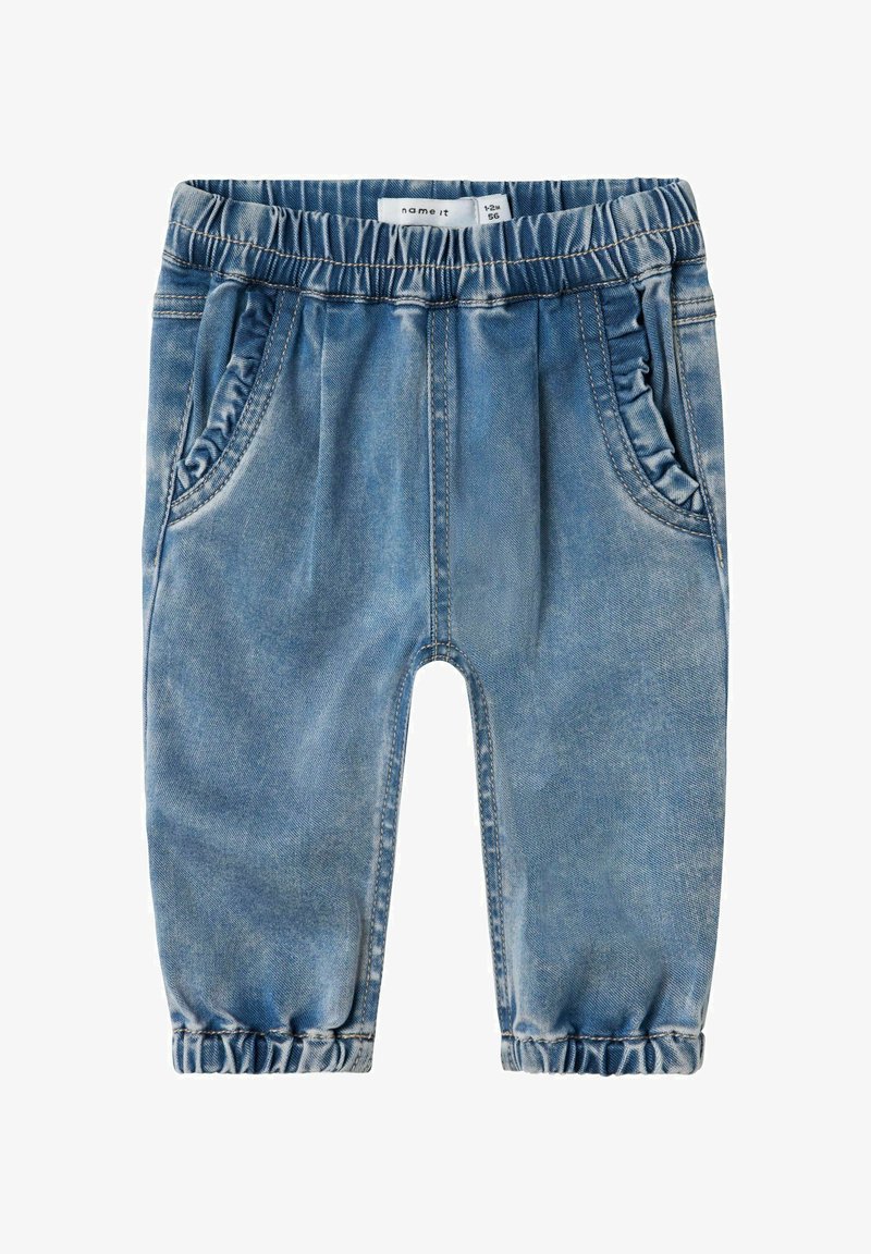 Los pantalones de mezclilla azul cuentan con una cinturilla elástica, bolsillos laterales y puños fruncidos en los tobillos. La tela tiene una textura desgastada.