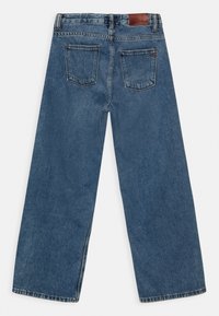 Blue denim wide-leg jeans with a high waist, featuring a brown leather patch at the back and two pockets on the rear. Smooth texture.