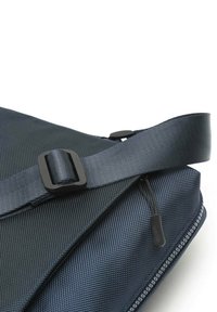 Borsa a spalla blu navy con superficie texturizzata, tracolla regolabile con fibbia e dettagli con chiusura a zip.