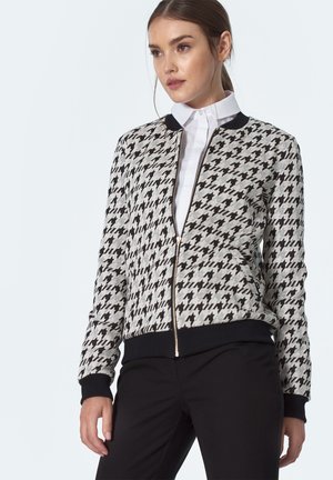Kurtka bomber w wzór houndstooth w odcieniach szaro-czarnych, posiadająca zamek błyskawiczny z przodu, ściągacze na rękawach oraz jednolitą czarną talię.