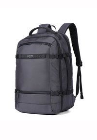 Sac à dos gris en tissu texturé, avec des bretelles réglables, une poche zippée à l'avant et des boucles sur les côtés pour un rangement et une stabilité supplémentaires.