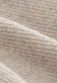 Țesătură de lână texturată, de culoare bej deschis, cu dungi subtile, cu o senzație moale și un aspect cald, ideală pentru îmbrăcăminte sau textile pentru casă.