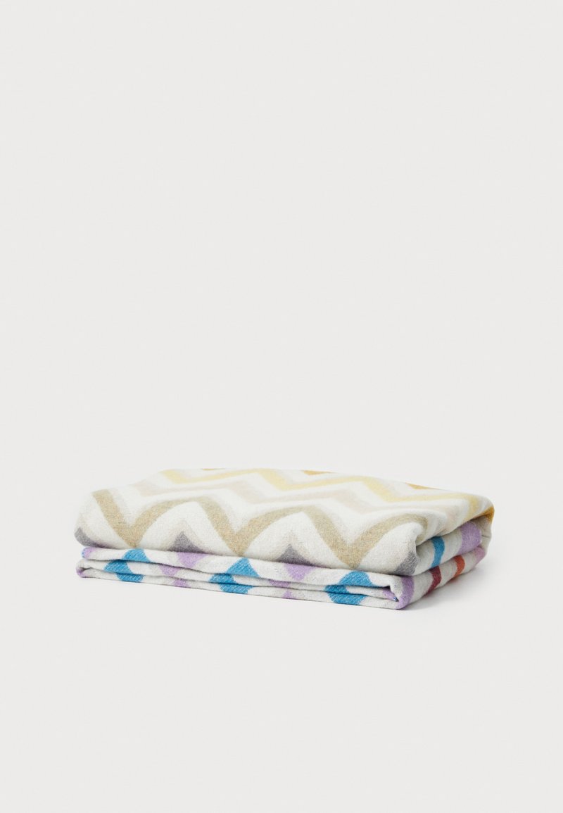 Flerfärgade mönstrade handdukar med ett chevronmönster i beige, vitt och blått, vikt prydligt med en mjuk textur.