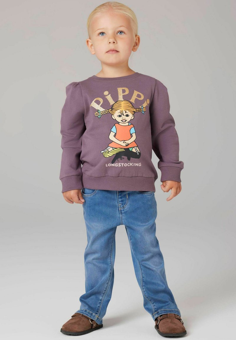 Felpa viola con una grafica di Pippi Calzelunghe, abbinata a jeans azzurri chiari e scarpe basse marroni. Tessuto morbido, vestibilità casual.