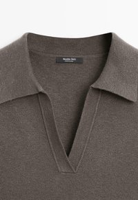 Maglione marrone a maglia con un ampio collo aperto e una piccola etichetta nera con la scritta "Massimo Dutti MADE IN CHINA" al collo.
