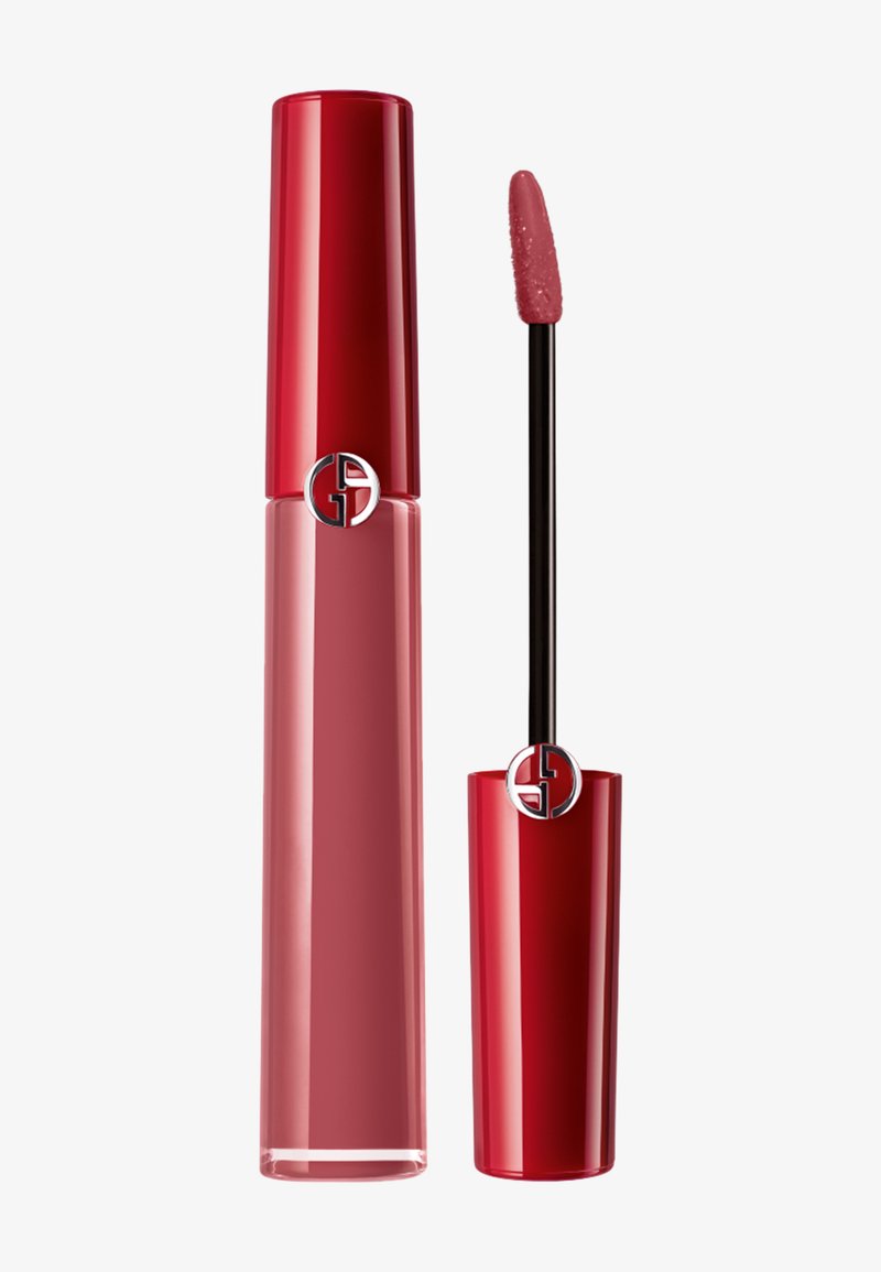 Rouge à lèvres liquide dans un tube transparent rose avec un capuchon rouge brillant. Comprend un applicateur noir avec un embout doux, offrant une finition lisse.