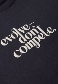 Sweatshirt en coton marine avec des lettres blanches texturées qui indiquent "évolue - ne concurrence pas." Le design comprend un col rond et des manches longues.