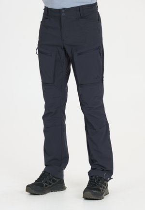 Schwarze Cargo-Hose für Herren mit mehreren Reißverschlusstaschen und schwarzen Wanderschuhen, dargestellt von der Taille bis zu den Füßen.