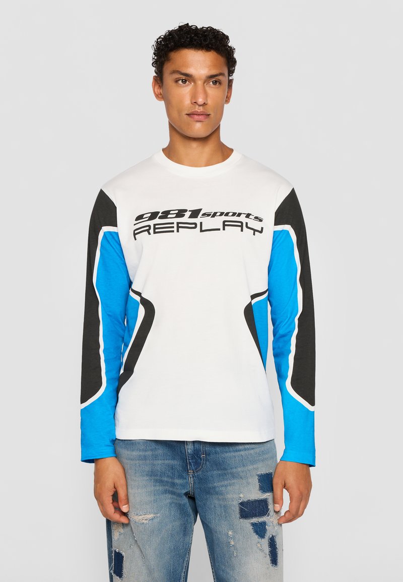 Long-sleeve t-shirt with a white body, blue and black sleeves, features bold black text "981sports REPLAY," and wave pattern accents.
