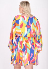 Rochie colorată cu imprimeuri abstracte, cu mâneci lungi, talie elastică și margine în straturi. Confeționată dintr-un material ușor și fluid, în nuanțe vibrante.