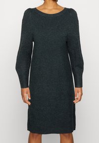 Stickad klänning i mörkgrön, med rund halsringning, långa ärmar och rak silhuett. Mjuk textur, minimala sömmar och avslappnad design.